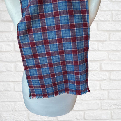 Plaid scarf draped over a mannequin against a white brick wall background