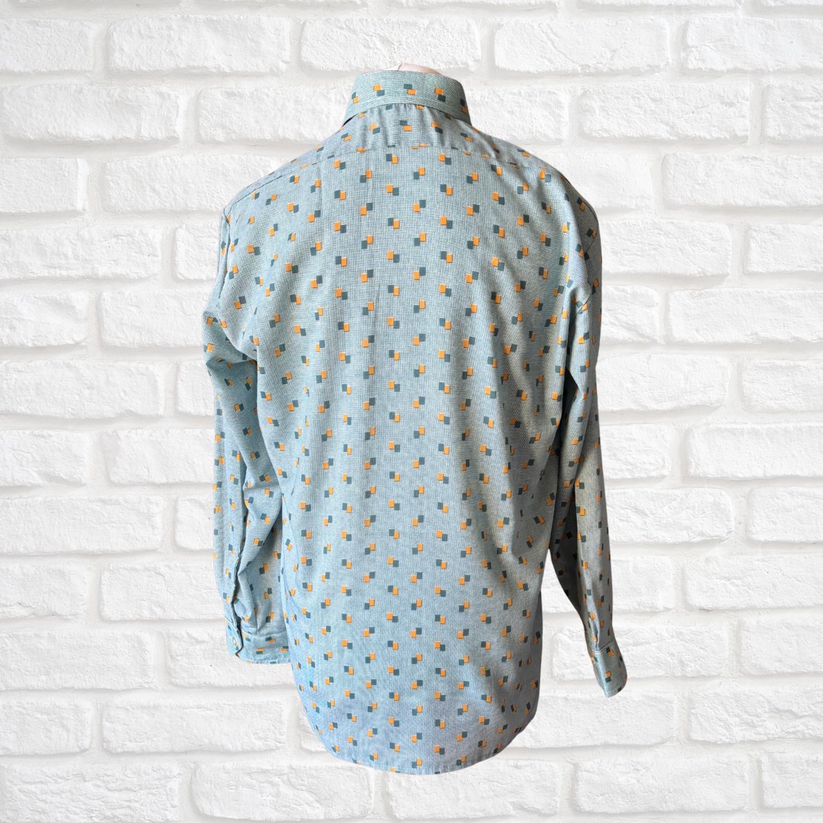 Light blue shirt with a geometric print on a white brick wall background