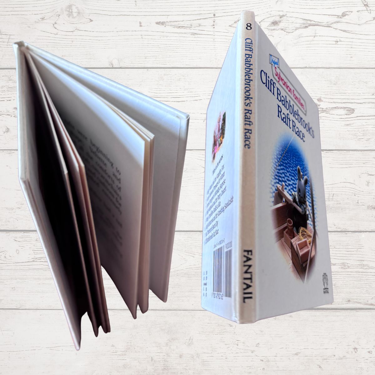 Book with open pages and a box labeled 'Cliff Babblebrook’s Raff Race' on a wooden surface