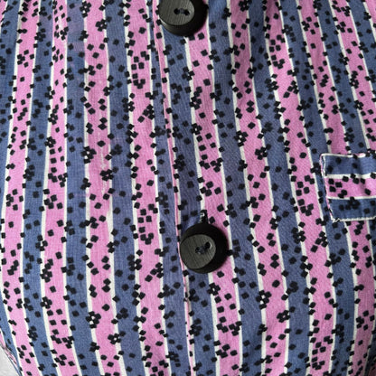 Close-up of a vintage dress with  pink and blue striped pattern and black speckles.