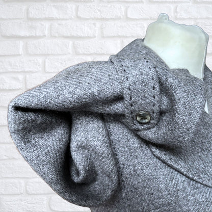 Close-up of a grey coat cuff  on a white brick wall background