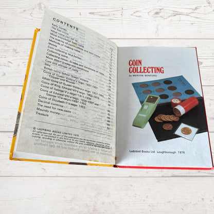 Open book on a wooden surface with a page titled 'Coin Collecting' by Mervyn Benson.