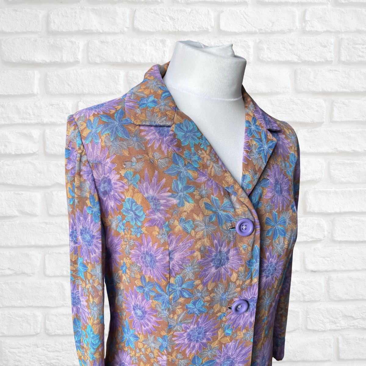 Floral patterned dress  on a mannequin against a white brick wall background