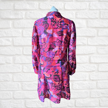Colorful floral-patterned shirt on a mannequin against a white brick wall background