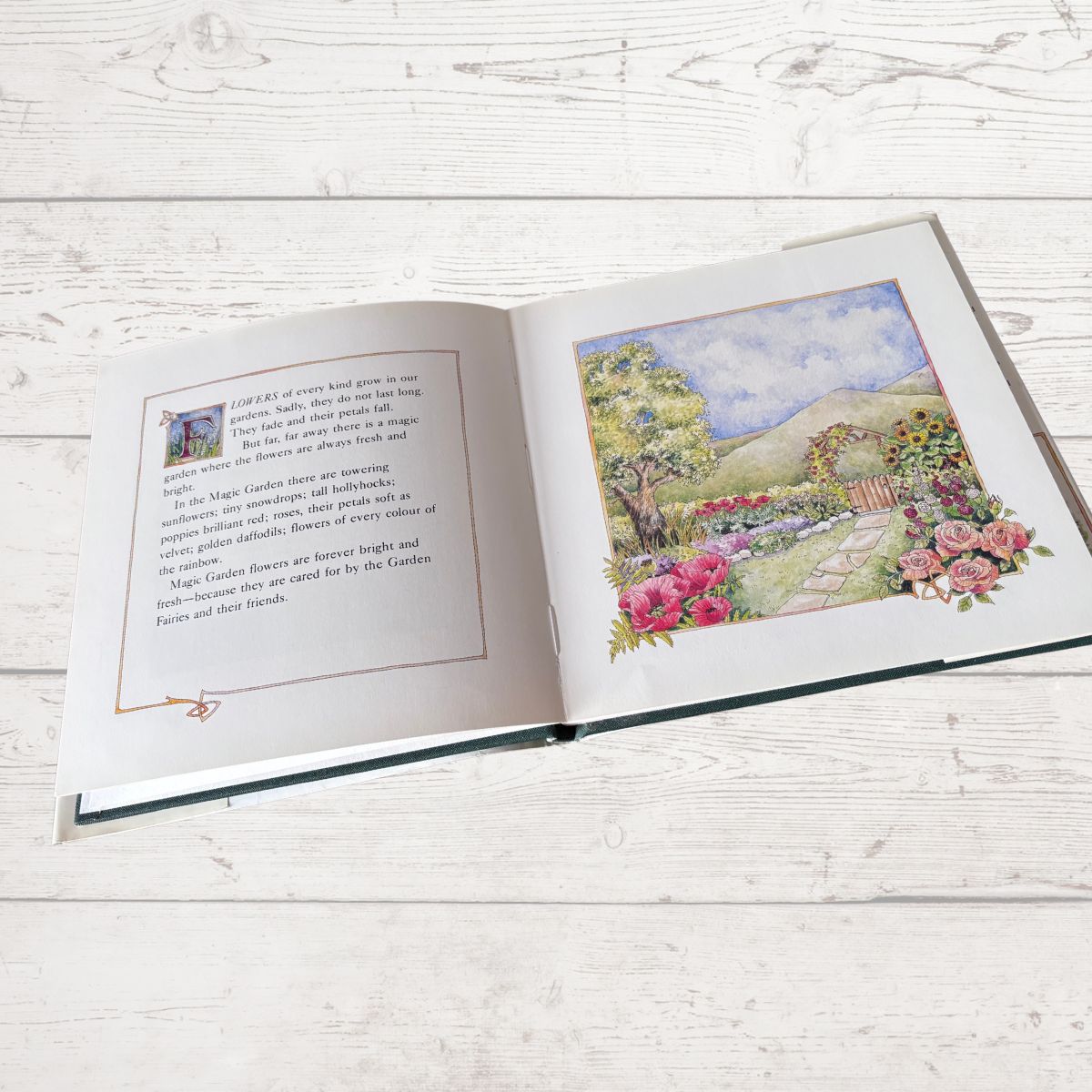 Open book with a colorful illustration of a garden on a wooden surface