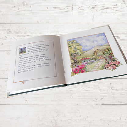 Open book with a colorful illustration of a garden on a wooden surface