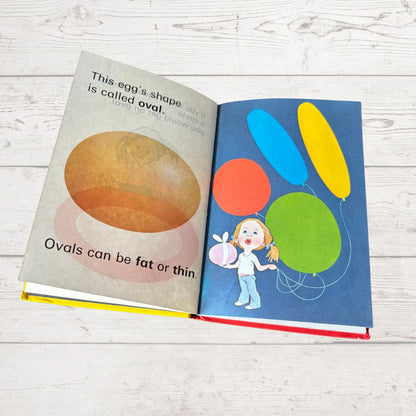 Open book showing educational content about eggs and shapes on a wooden surface
