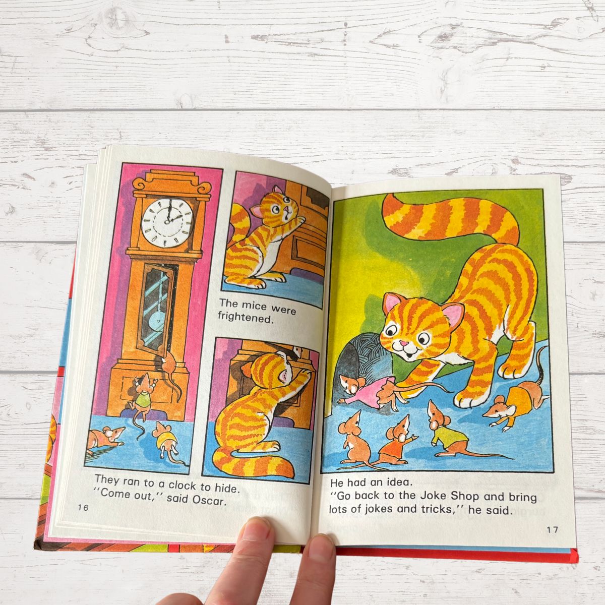 Open children's book with colorful illustrations of a cat and mice on a wooden surface