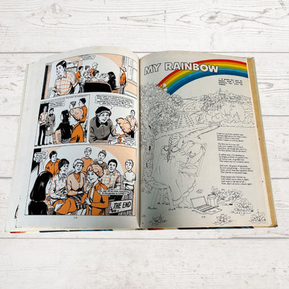 Open book with comic strip and coloring page on a wooden surface