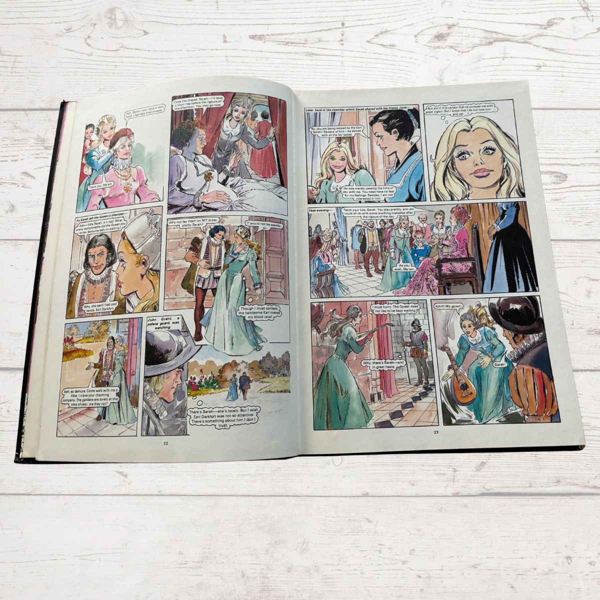 Open book with illustrated comic pages on a wooden surface