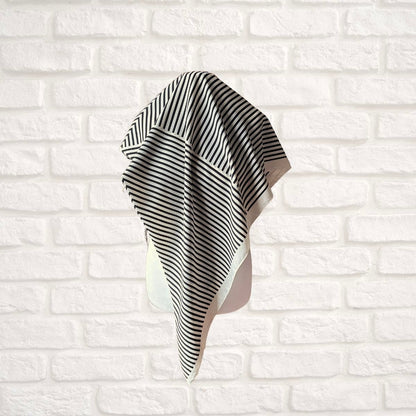 Black and white striped scarf  draped over a white brick wall