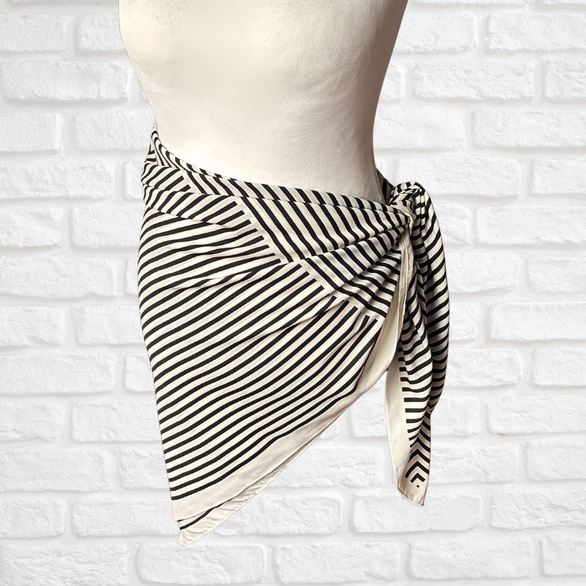 Striped scarf on a mannequin against a white brick wall background