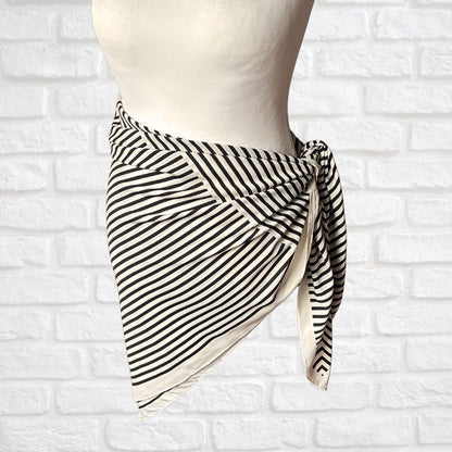 Striped scarf on a mannequin against a white brick wall background