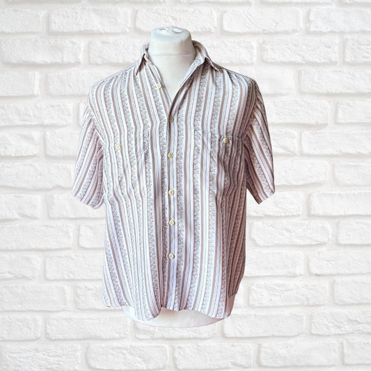 A short-sleeve button-up shirt with vertical textured stripes in beige, brown, and white, displayed on a white mannequin torso against a white brick wall background.