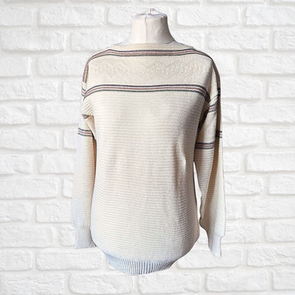 A cream-colored ribbed knit sweater with thin horizontal stripes, displayed on a mannequin torso against a white brick wall background.