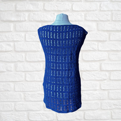 A royal blue open-knit sleeveless top displayed on a light blue mannequin torso against a white brick wall background.