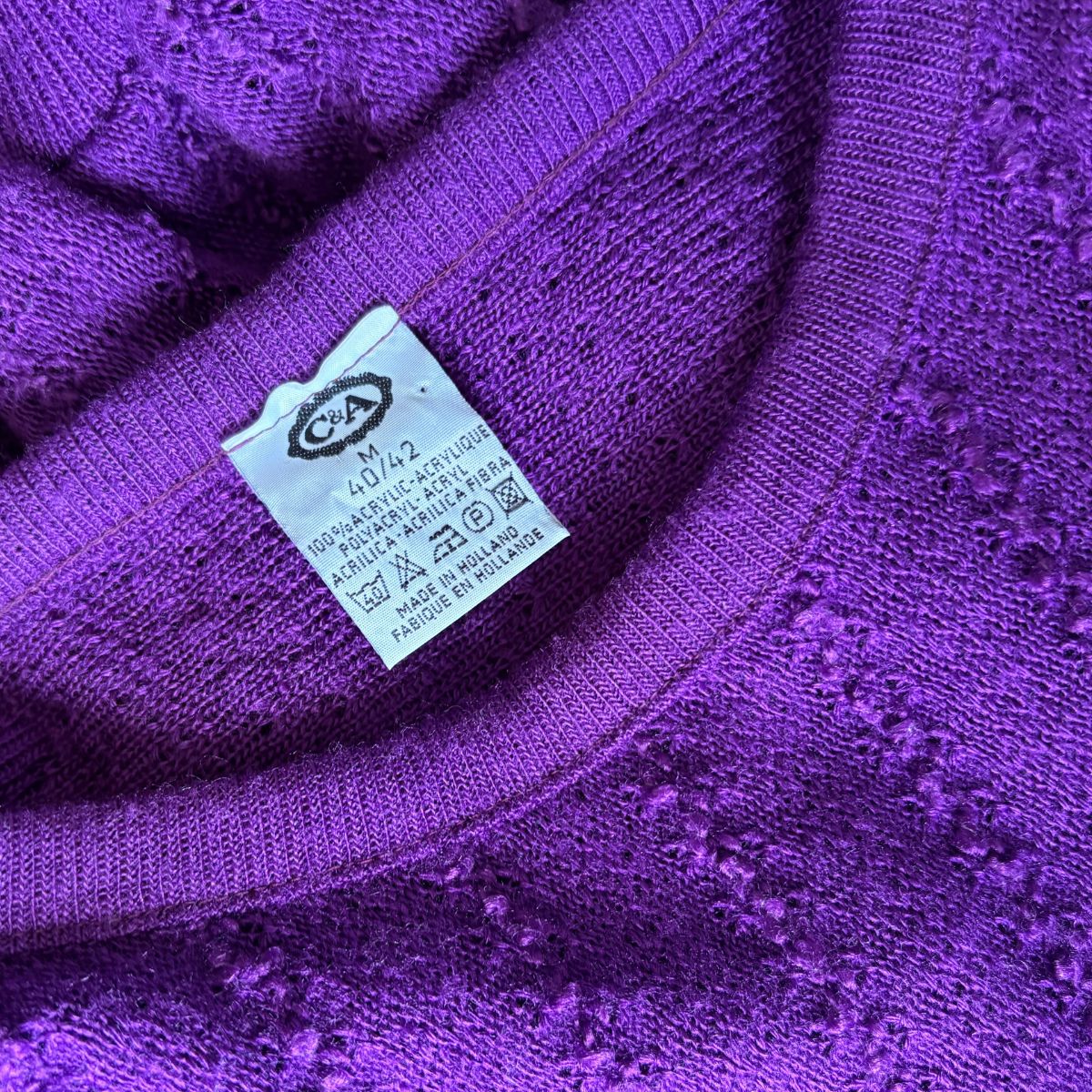 Close-up of a purple knit garment showing the inner neck and a white care label with a CSA logo.