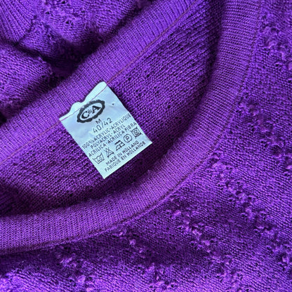 Close-up of a purple knit garment showing the inner neck and a white care label with a CSA logo.