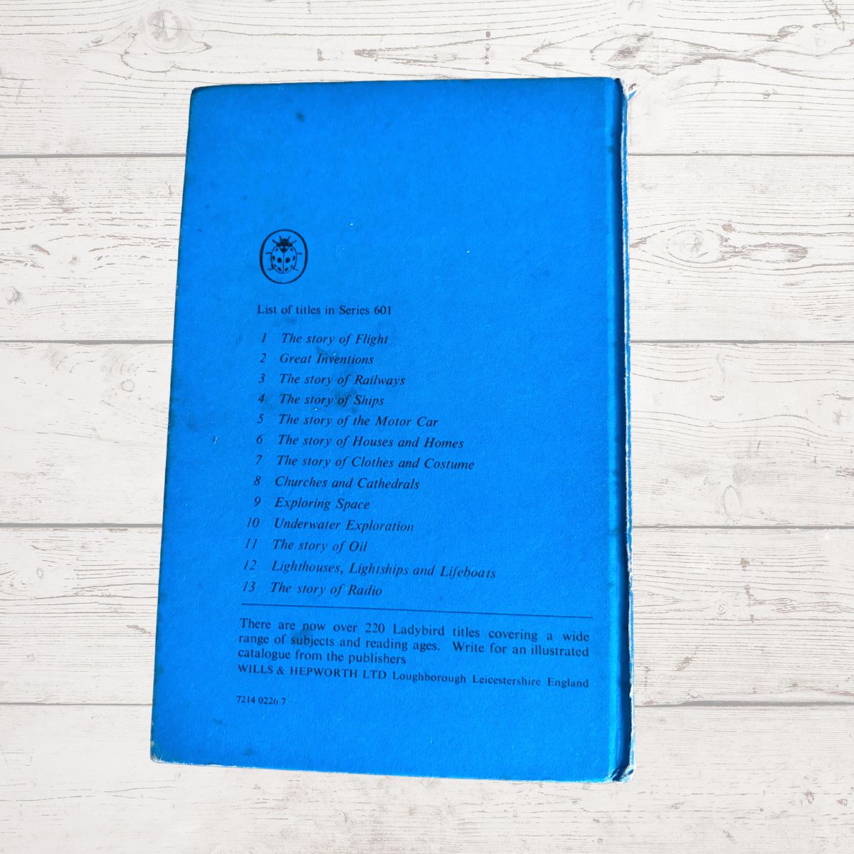 A vintage blue booklet or book cover titled 'List of stories in Series 601' with a list of stories printed on it, photographed on a white wood plank background.