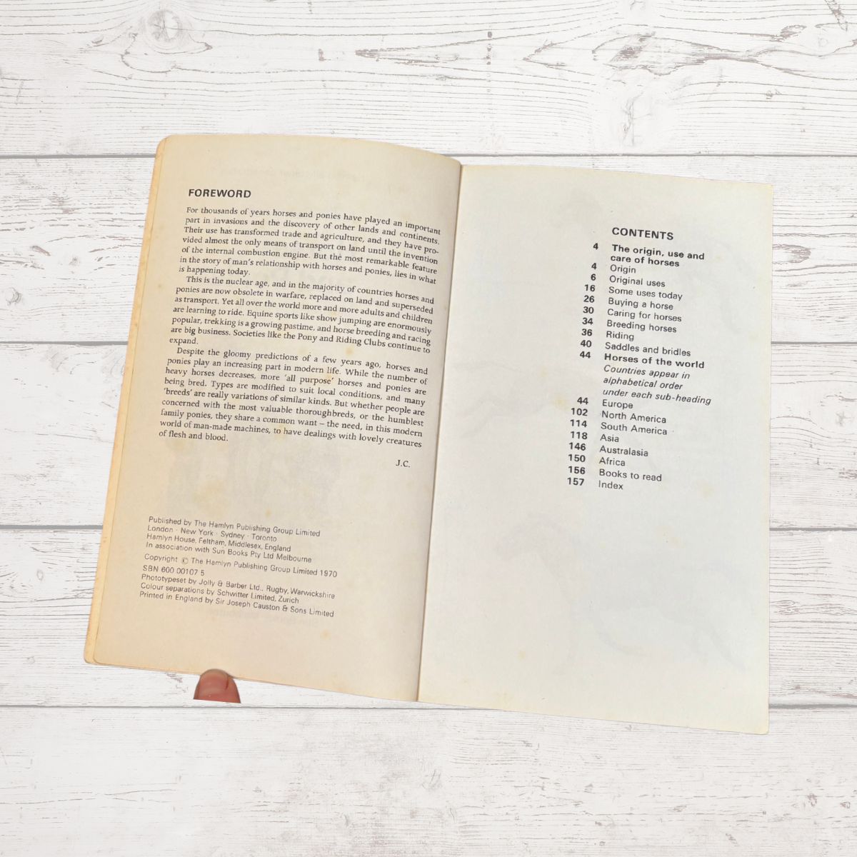 An open book showing the foreword and contents pages, photographed from above on a white wood plank surface.