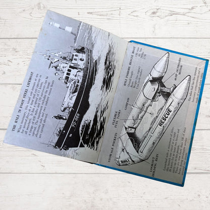 An open vintage booklet or book spread laid on a light wood surface, showing black-and-white illustrations and text about a rescue boat and its parts. The booklet has a blue border and is photographed from above.