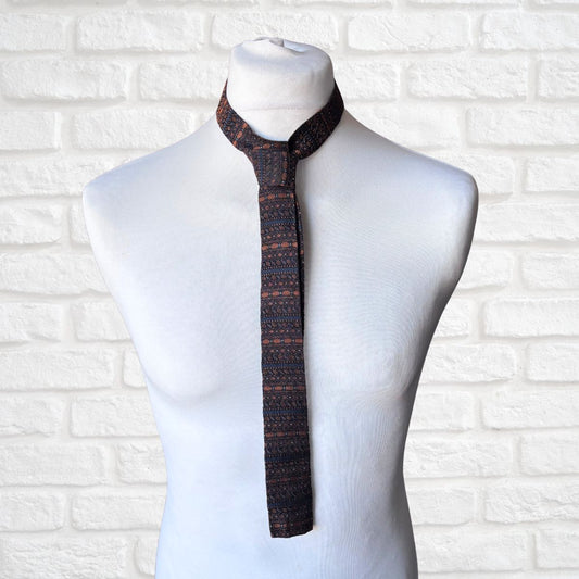 Patterned tie on a mannequin against a white brick wall background