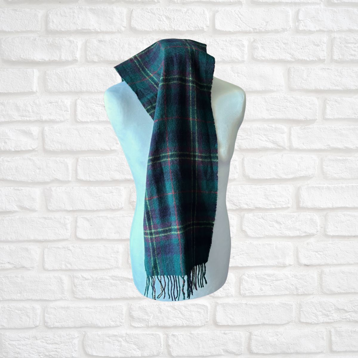Plaid scarf on a mannequin against a white brick wall background