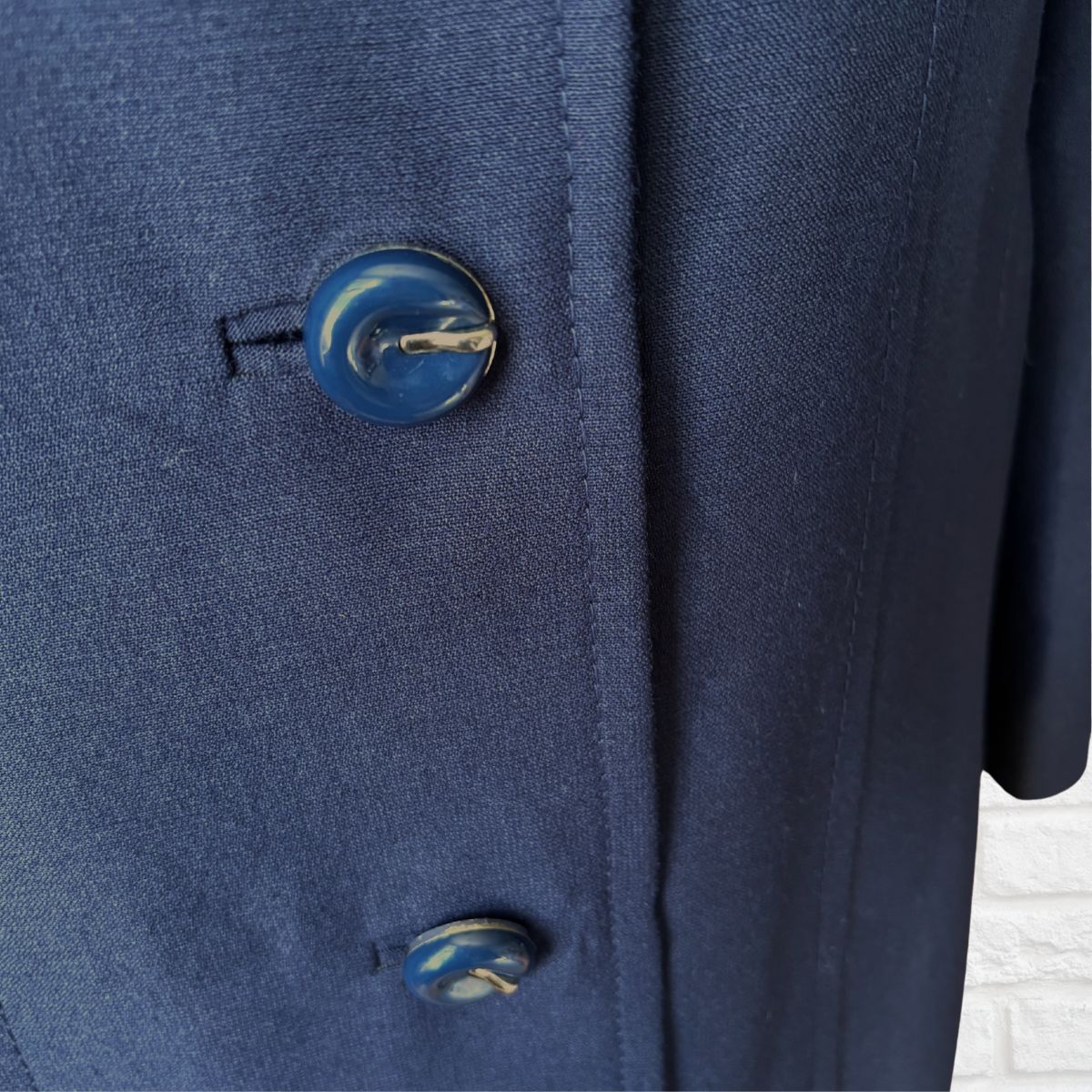 Close-up of a navy blue textured fabric garment with two decorative blue and white marbled buttons.