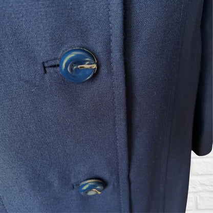 Close-up of a navy blue textured fabric garment with two decorative blue and white marbled buttons.