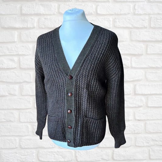 Dark brown/green cardigan on a mannequin against a white brick wall back