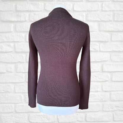 A dark brown  ribbed knit long-sleeve top displayed on a mannequin torso against a white brick wall background.