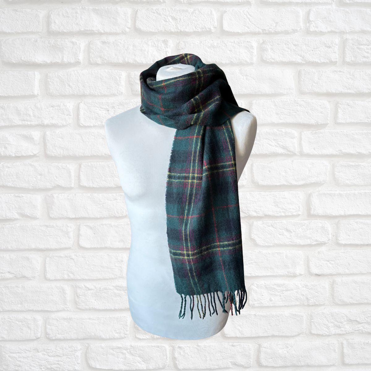 Plaid scarf on a mannequin against a white brick wall
