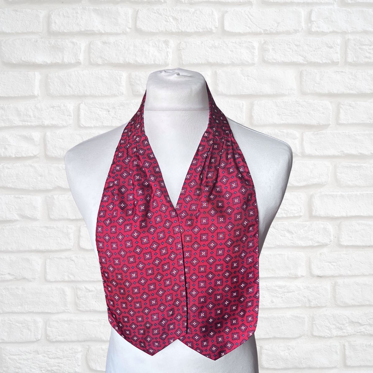 Red patterned cravat on a mannequin against a white brick wall background