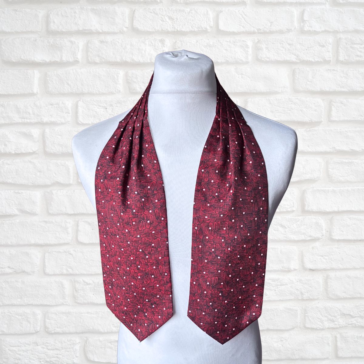 Red patterned cravat on a mannequin against a white brick wall background
