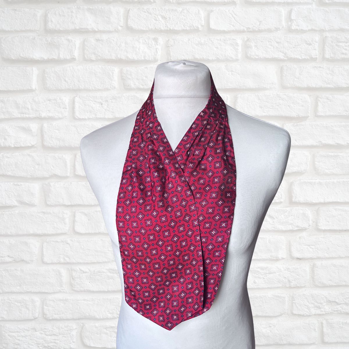 Red patterned cravat on a mannequin against a white brick wall background