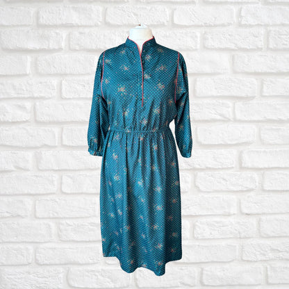 Teal patterned dress on a mannequin against a white brick wall background