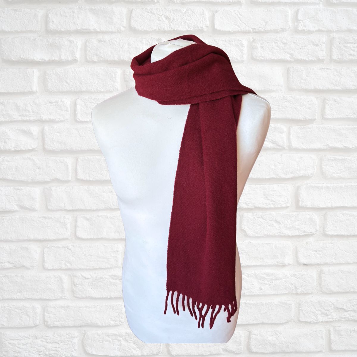 Red scarf on a mannequin against a white brick wall background