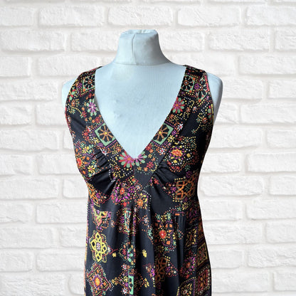 Colorful patterned dress on a mannequin against a white brick wall.