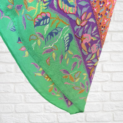 Colorful embroidered fabric with floral patterns on a white brick wall background