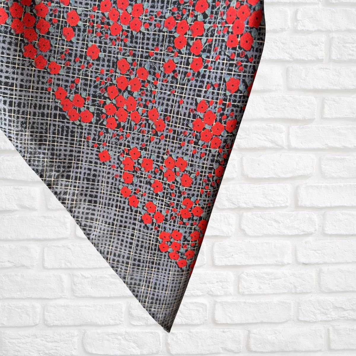 Red floral pattern on a gray fabric against a white brick wall background