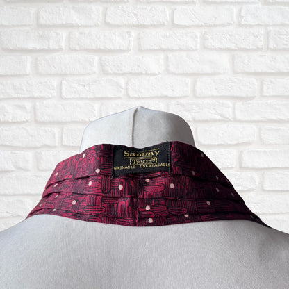 Mannequin wearing a red patterned cravat  with 'Sammy' branding against a white brick wall.