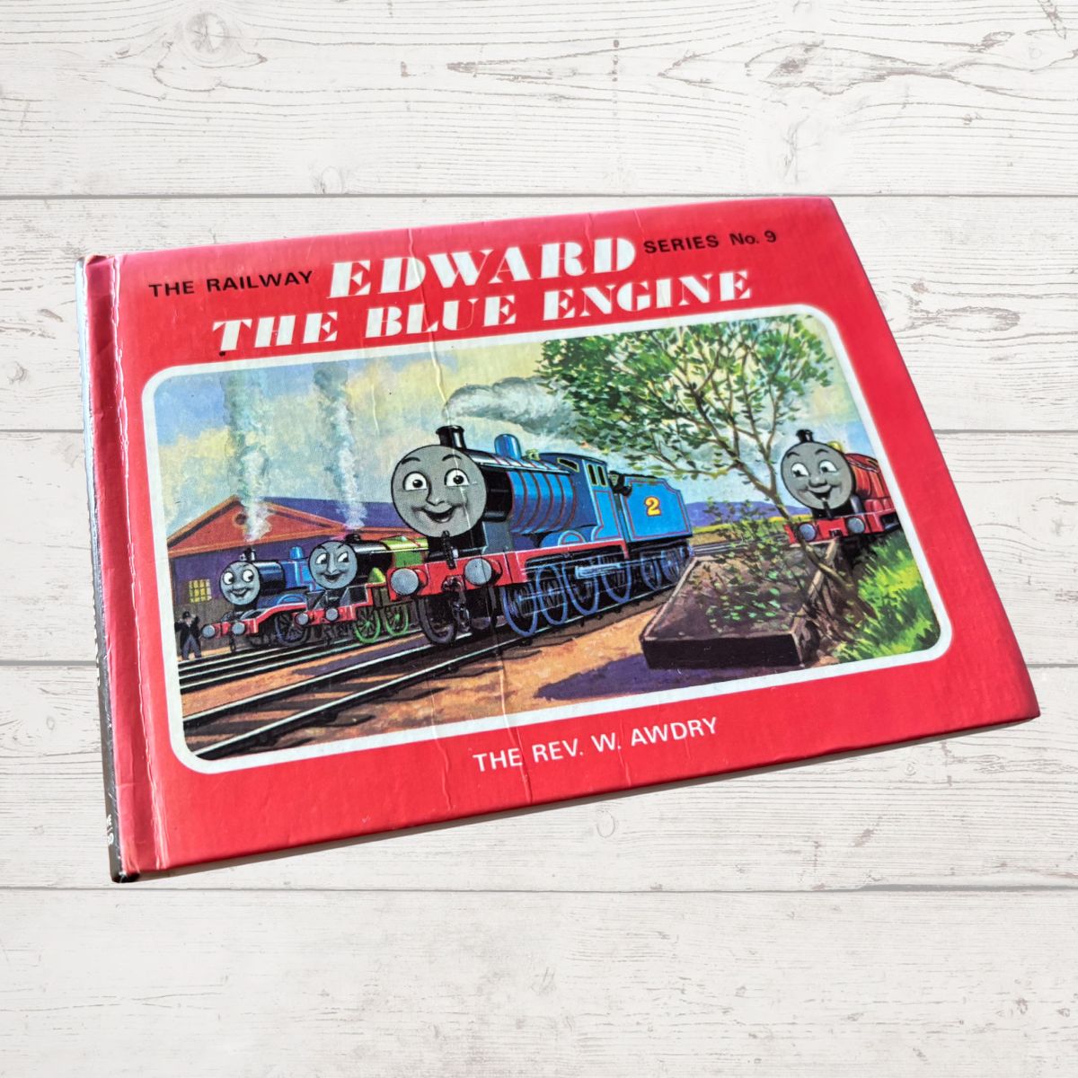 Book titled 'Edward the Blue Engine' by Rev W. Awdry on a wooden surface