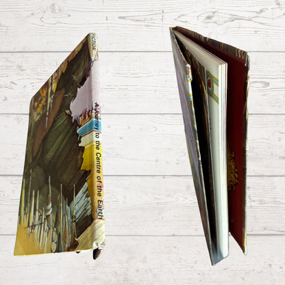 A hardcover book shown from two angles on a white wood background. The left view shows the illustrated front cover with the spine visible, and the right view shows the open interior pages and a reddish inner cover.