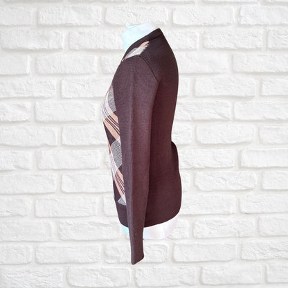A dark brown knit  sweater with a beige and white  plaid pattern panel on the side, displayed on a white mannequin torso against a white brick wall background.