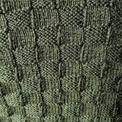 Close-up of a dark olive green textured knit fabric with a basketweave pattern.