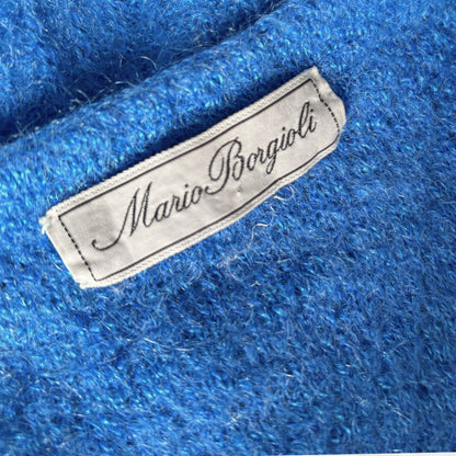 Close-up of a bright blue textured knit fabric with a white embroidered label reading Mario Borgioli.