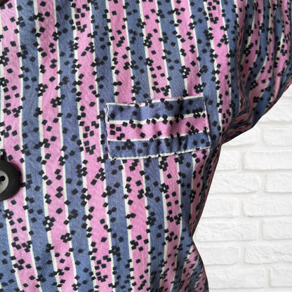 Close-up of a vintage dress with pink and blue striped pattern on a white brick wall background