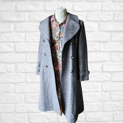 Grey coat open on a mannequin against a white brick wall background