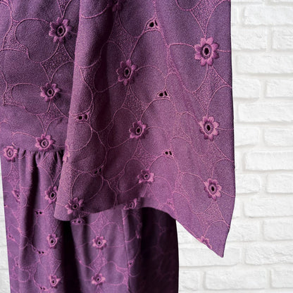 Purple floral patterned fabric against a white brick wall