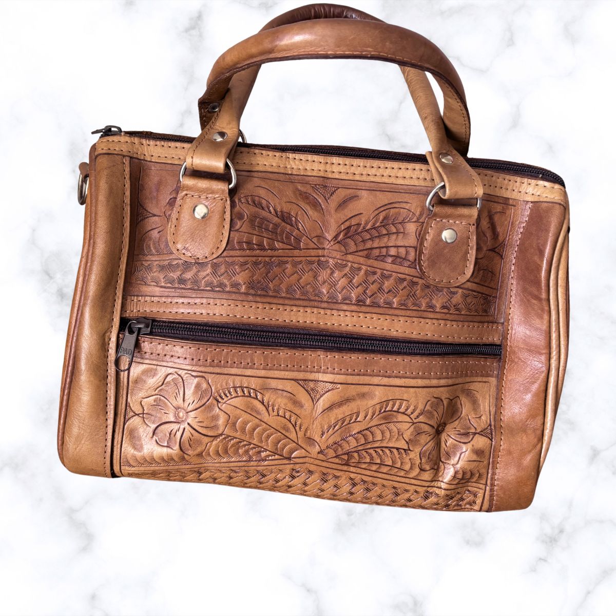 Brown leather handbag with floral embossing on a white background